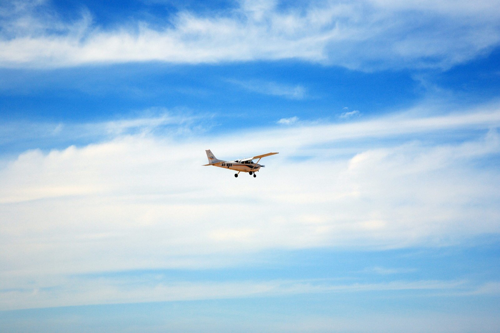 white and black airplane flying under blue sky during daytime